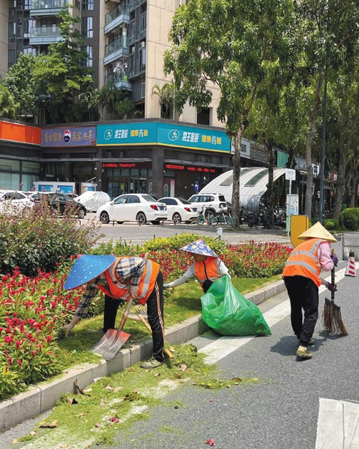 عمال يرتدون قبعات أثناء عملهم في الشمس وسط إنذار أصفر لموجة الحر في مقاطعة جوانجدونج بالصين. (رويترز)