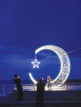 رجل وزوجته يلتقطان صورا لطفلهما أمام زخرفة على شكل هلال وضعت في مدينة أولسينج خلال شهر رمضان. ا ف ب