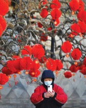 امرأة تلتقط صورة بجوار شجرة مزينة بفوانيس ورقية عند مدخل حديقة خلال احتفال الصين بالعام القمري الصيني الجديد في بكين «ا ف ب»