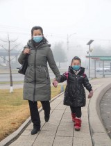 امرأة وابنتها ترتديان الكمامة وتسيران على طول شارع علماء ميرا في بيونغ يانغ. ا ف ب