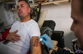 يدق وشماً على ذراعه لوجه عالم أوبئة شهير