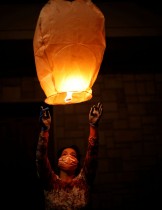 امرأة ترتدي قناع وجه واقٍ تضيء فانوساً ورقياً أثناء حضورها احتفالًا تخليدا لذكرى الذين ماتوا بسبب تفشي مرض فيروس كورونا في بلدة سان جورجيو إيونيكو الجنوبية الصغيرة بإيطاليا.   رويترز